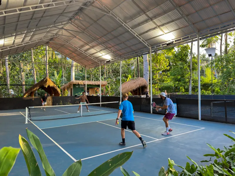Doubles rally on the covered court, jungle all around